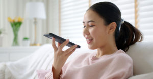 Woman speaking into smartphone while using a voice-based AI assistant.